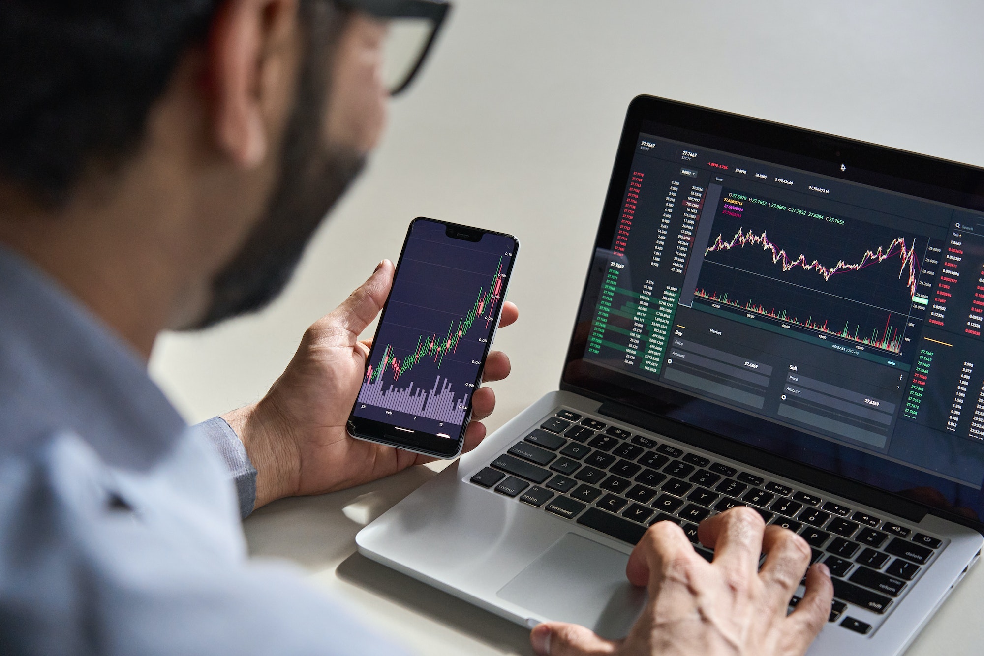 Trader analysing live market data on laptop and phone